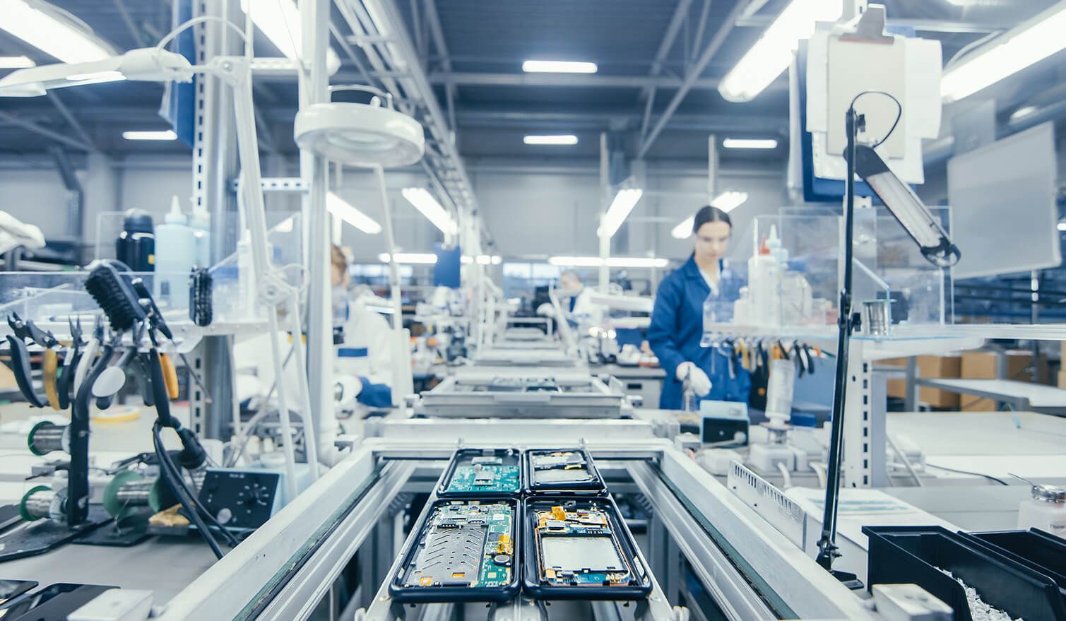 Pracownicy w zakładzie produkcyjnym, montujący podzespoły elektroniczne w odpowiednio zaprojektowanym oświetleniu