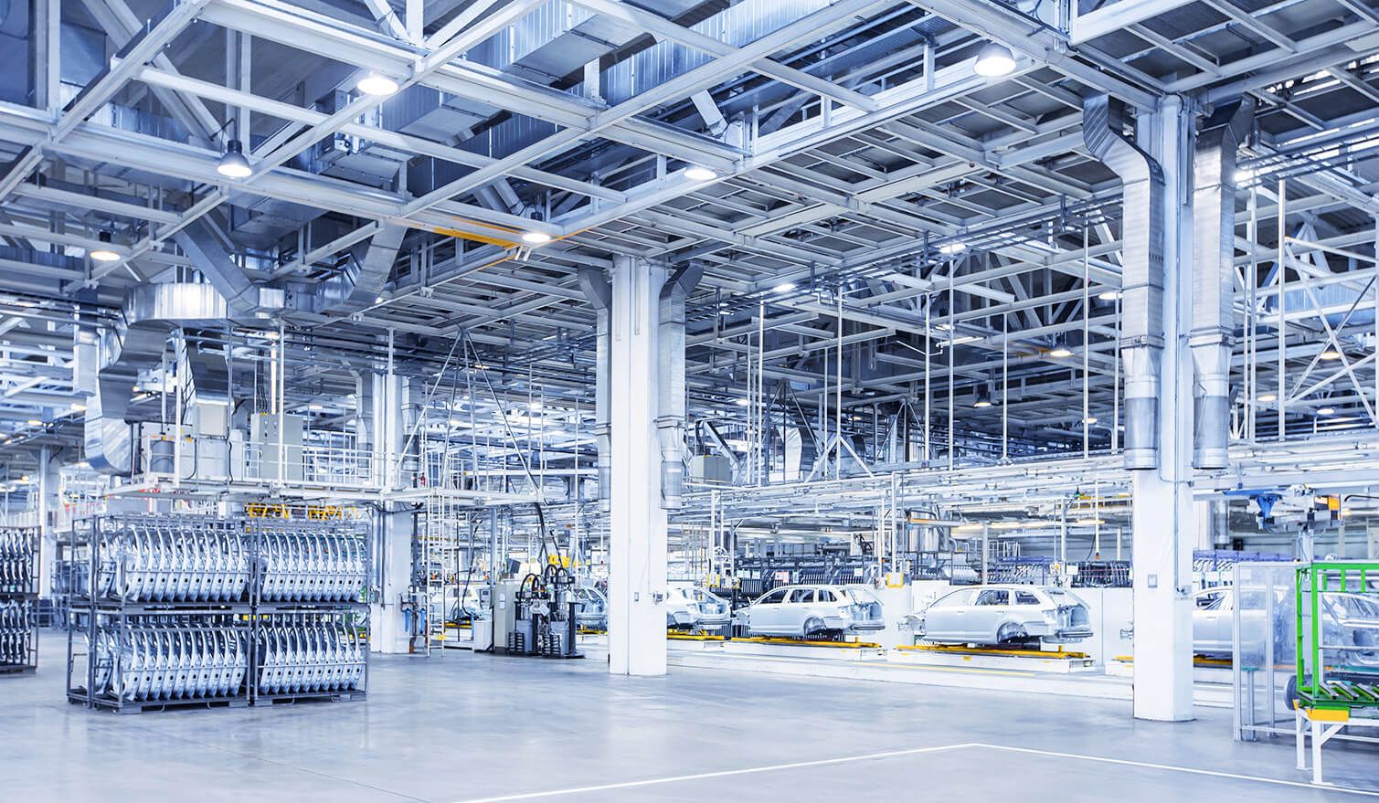 Duża fabryka z wieloma samochodami i ciężarówkami, ukazująca nowoczesne oświetlenie w procesie produkcji automotive