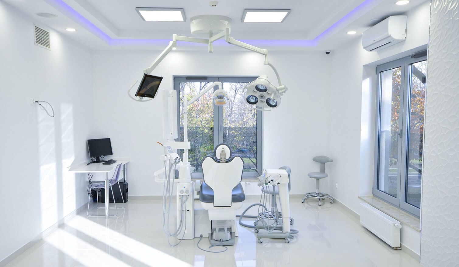 Wnętrze gabinetu dentystycznego z fotelem, komputerem i lampą, podkreślające znaczenie odpowiedniego oświetlenia w stomatologii | Lumedic
