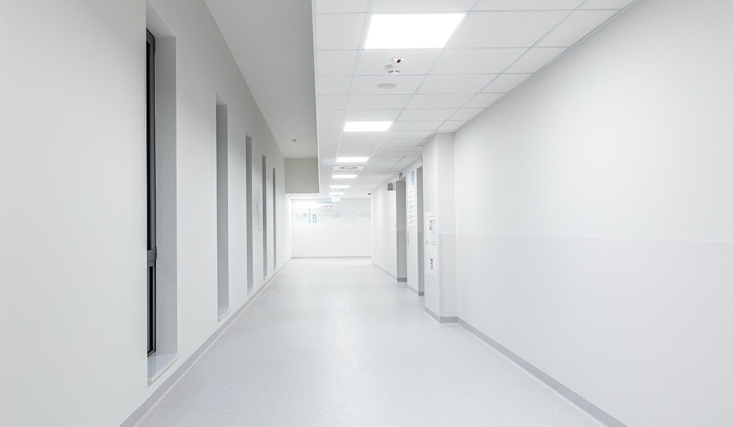 Długi korytarz szpitalny z białymi ścianami i jasnym oświetleniem, zapewniający komfort pacjentów i personelu medycznego |  Lumedic 